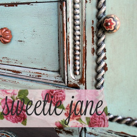 Distressed teal furniture finished in Sweetie Jane, with ornate knobs and floral accents over pink rose detailing.