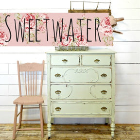 Pink chair and pale green dresser in Old Fashioned Milk Paint beside a Sweetwater sign on white shiplap wall.