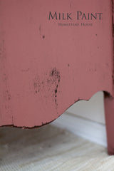 Distressed pink wood furniture finished with Homestead House Texas Rose Milk Paint, shown in close-up.