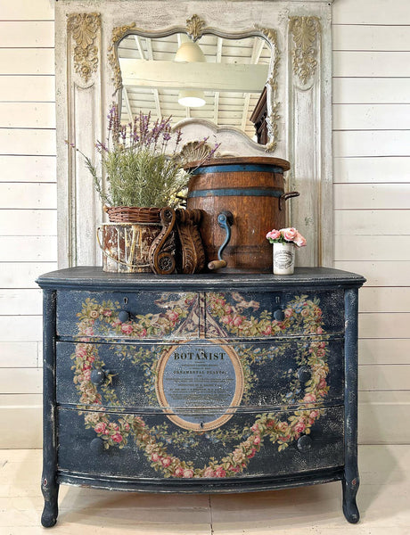 Vintage dresser with I.O.D. Botanist Transfer, topped with a mirror and plants.
