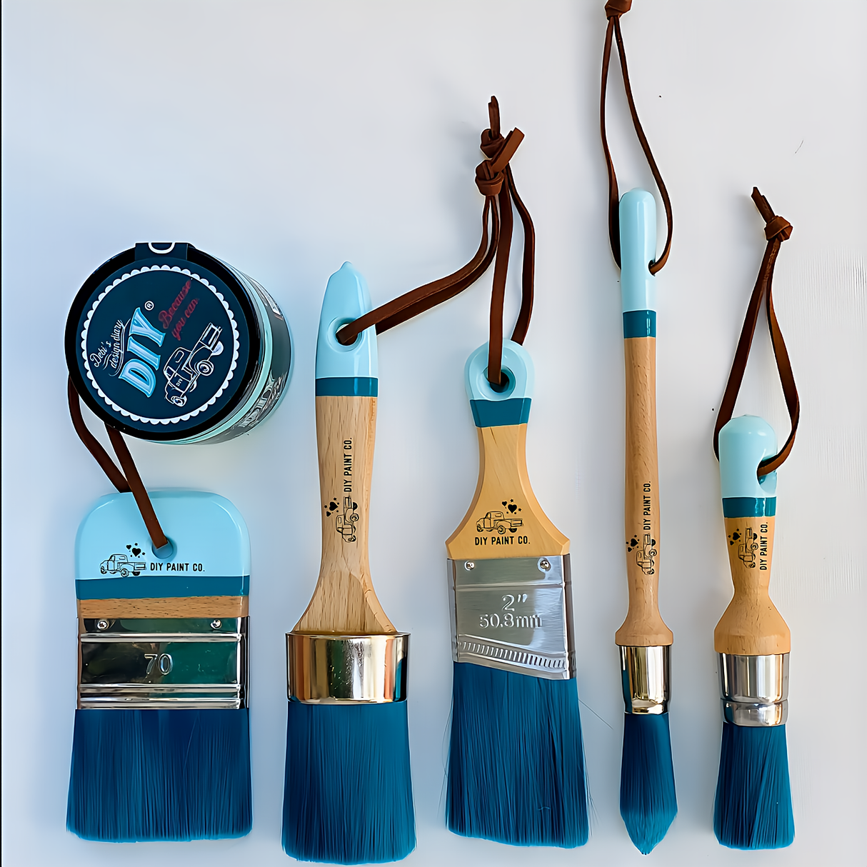 Four DIY Paint Co. Feather paintbrushes and a blue can displayed on a white surface.