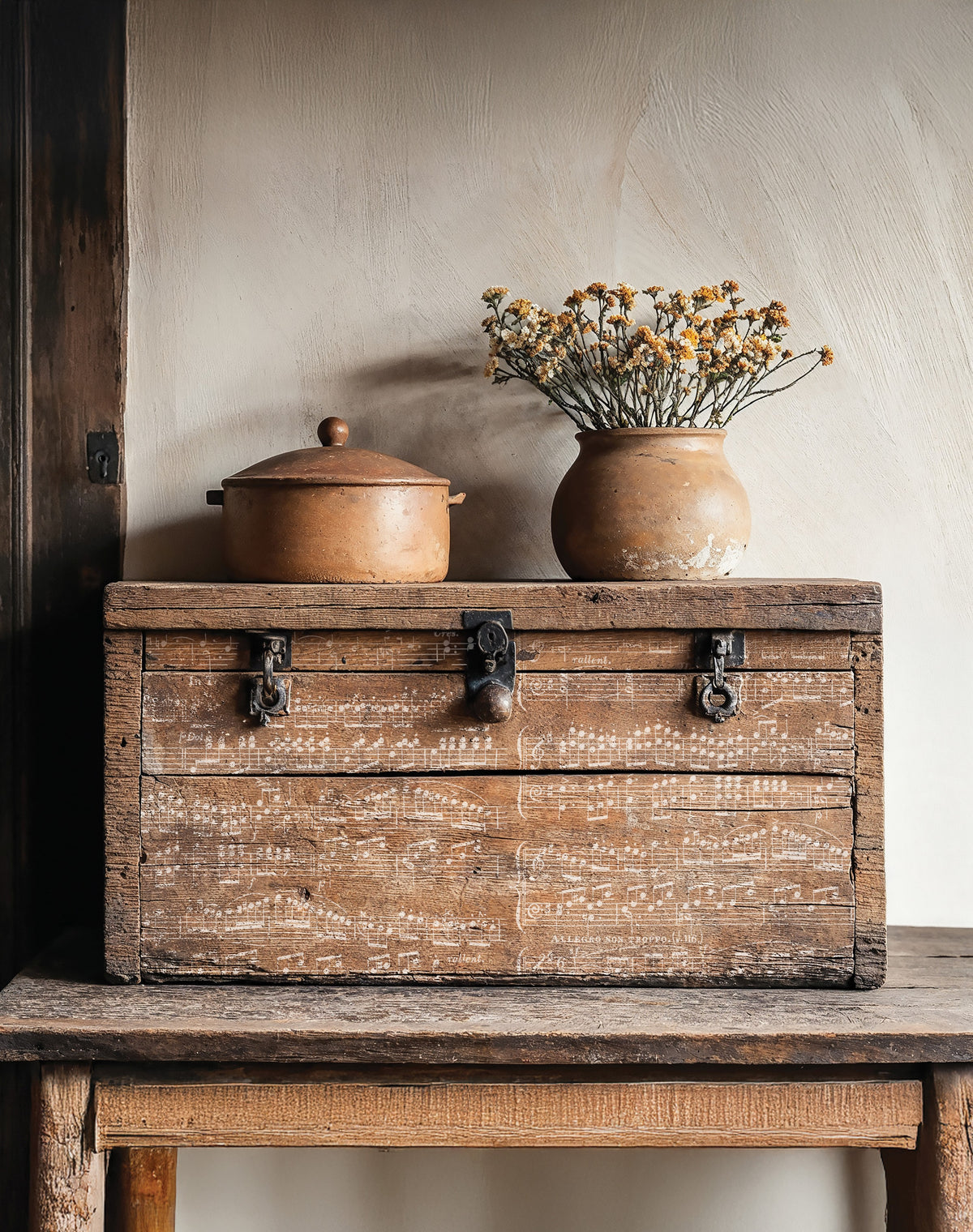 The Waltz Stamp by IOD displayed on a wooden chest with vintage sheet music and a vase of dried flowers on top.