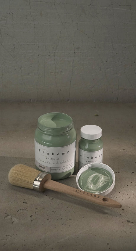 Brush, Thyme Alchemy Paint by Fusion Mineral Paint, and jars arranged on concrete.
