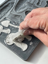 Hand applying plaster to I.O.D. Toadstool Mould by Iron Orchid Designs on a white surface.
