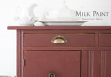 Maroon cabinet in Trading Post Red Milk Paint by Homestead House, topped with white ceramic dishes.