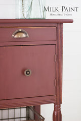 Wooden cabinet in Trading Post Red Milk Paint by Homestead House with metal knobs; “Homestead House” text upper right.
