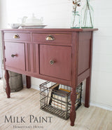 Red wood sideboard in Homestead House Trading Post Red Milk Paint, books underneath, jars and dishes on top.