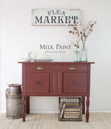 Red sideboard in Homestead House Trading Post Red Milk Paint with white dishes, cotton bouquet, and old milk can.