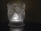 Frosted vase featuring I.O.D. Tulips Mould decor, illuminated from below on a dark reflective surface.