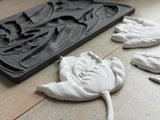 White clay tulip beside IOD Tulips Mould on light wood, in Iron Orchid Designs style.