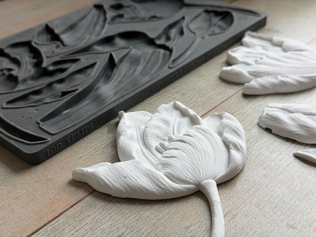 White clay tulip beside IOD Tulips Mould on light wood, in Iron Orchid Designs style.
