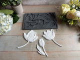 I.O.D. Tulips Mould by Iron Orchid Designs with three white clay tulips on wood, surrounded by artificial flowers.