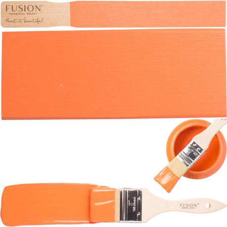 Wooden brush next to open jar of Fusion Mineral Paint in Tuscan Orange on white background.