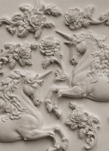 Two white-relief unicorns and flowers made with the Unicorns Mould by IOD on a flat surface.