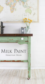 Distressed table in Upper Canada Green Milk Paint by Homestead House with yellow flowers displayed on top.