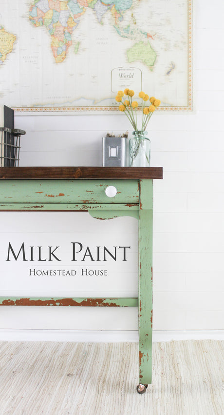 Distressed table in Upper Canada Green Milk Paint by Homestead House with yellow flowers displayed on top.