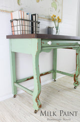 Distressed desk in Upper Canada Green Milk Paint with books, a map, and vase on top.