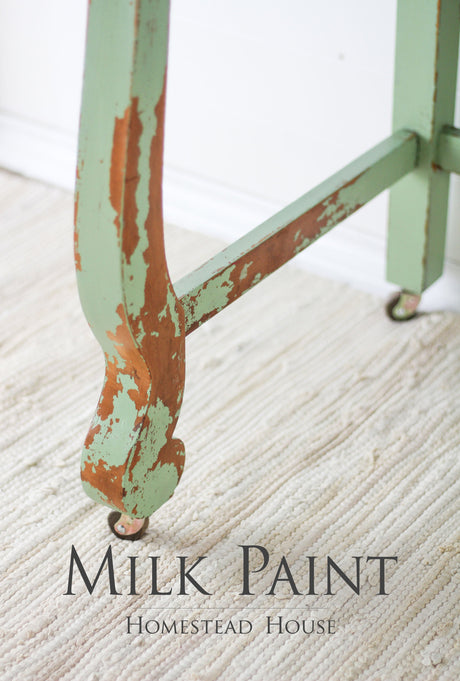 Chipped table leg painted in Upper Canada Green Milk Paint by Homestead House; text: Homestead House.