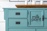 Teal cabinet with black handles painted in Fusion Mineral Paint Velvet Palm, candles on a wooden tray on top.