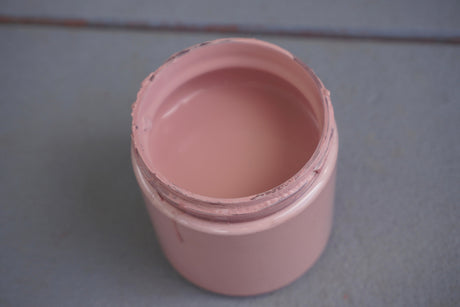 Open jar of Veranda DIY Cottage Color by DIY Paint Co. on a blue-gray surface.