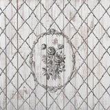 The Veranda Stamp by I.O.D. with a black floral design in an ornate oval over bamboo lattice wooden planks.