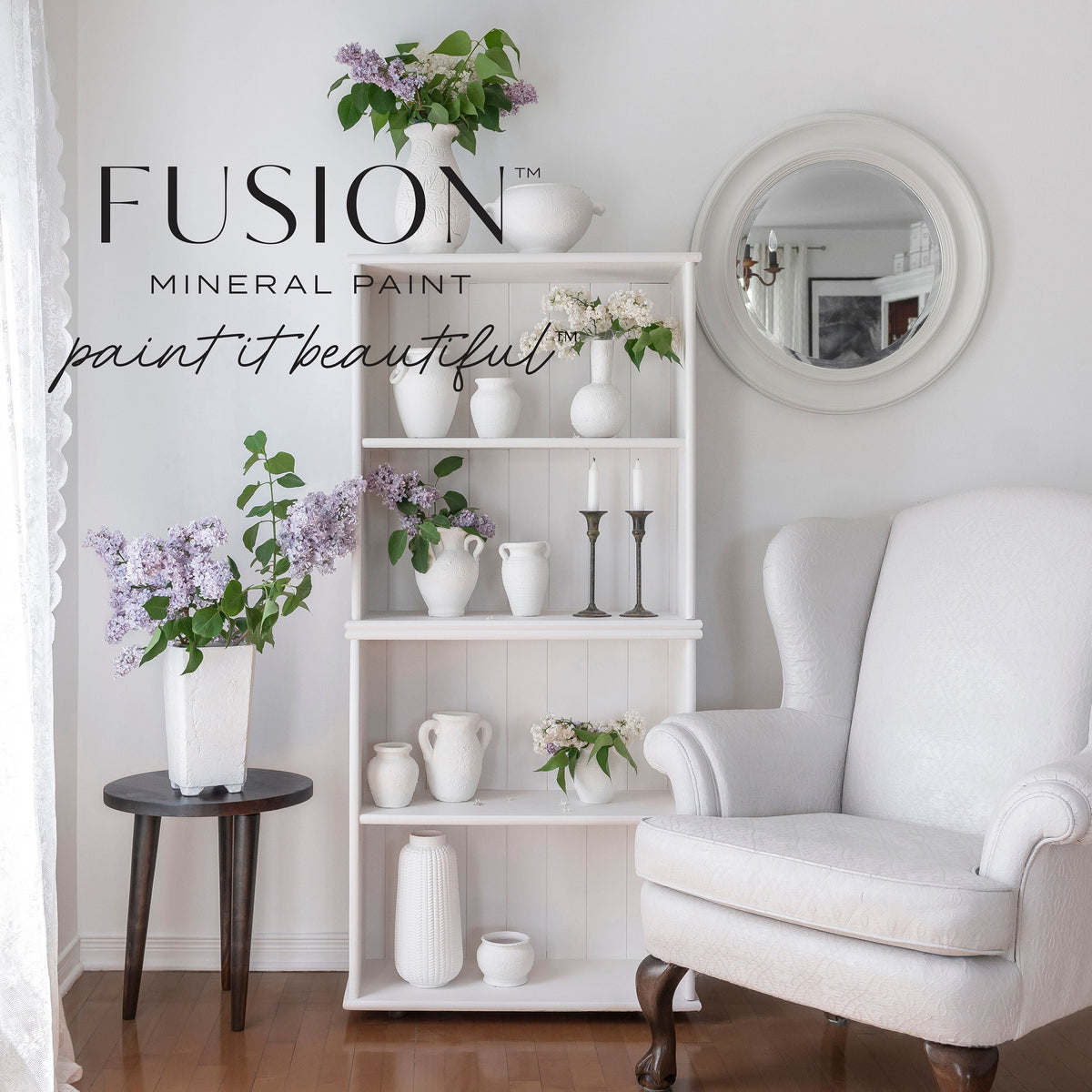 White armchair and shelf painted in Victorian Lace by Fusion Mineral Paint, logo near a round mirror and lilacs.