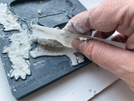 Plastic scraper applying plaster to IOD Village Market Mould, forming raised shapes by Iron Orchid Designs.