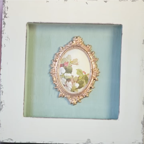 Small oval floral painting in gold frame, resembling I.O.D. Vintage Brooches Mould, set in distressed shadow box.