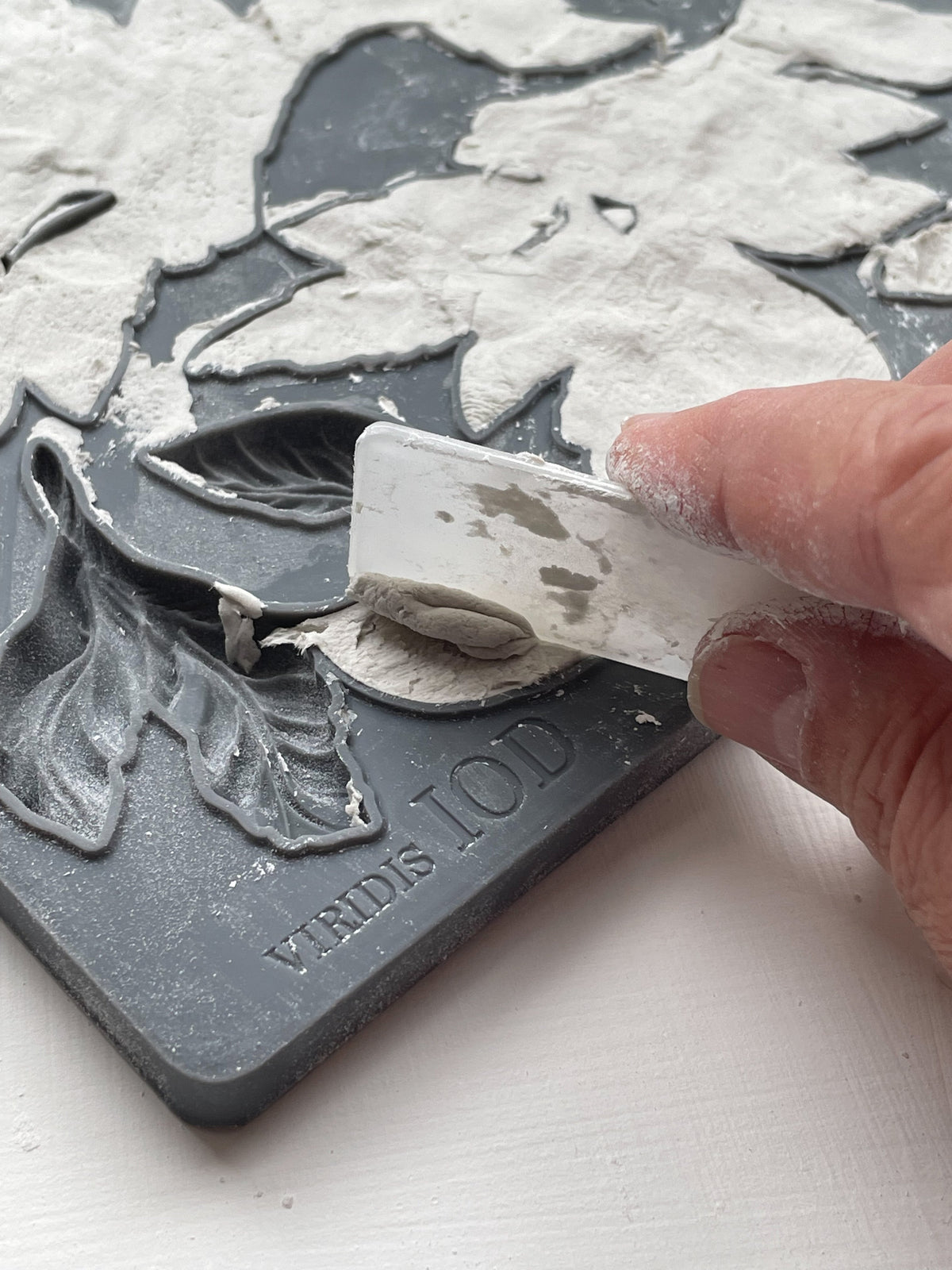 Hand removes clay from I.O.D. Viridis Mould using white tool on gray FREDIS TOOLS tray.