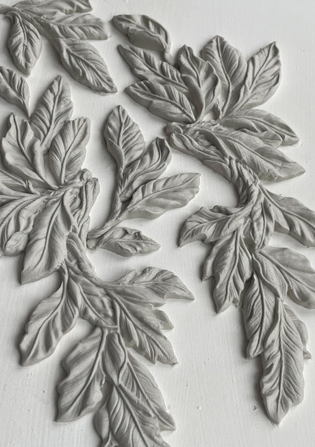 White clay leaves with detailed veins made with I.O.D. Viridis Mould by Iron Orchid Designs, arranged on white.