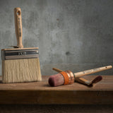 Three brushes, including a Staalmeester Wall Brush Series 3005, displayed on wood.
