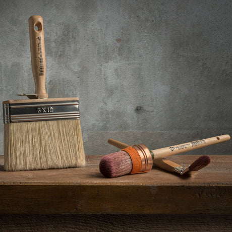 Three brushes, including a Staalmeester Wall Brush Series 3005, displayed on wood.