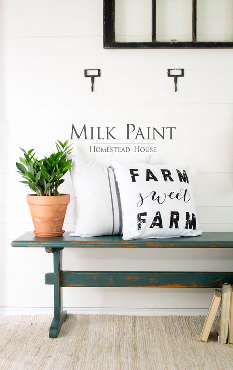 Bench in Homestead House Waterloo Green Milk Paint with potted plant, white pillows, books, MILK PAINT HOMESTEAD HOUSE wall.