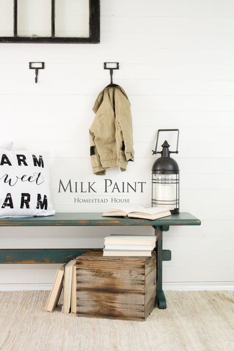 Khaki jacket displayed above a bench with books and a crate, highlighted by Homestead House Waterloo Green Milk Paint.