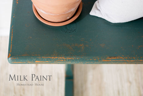 Green table in Waterloo Green Milk Paint by Homestead House, with terracotta pot and gray cushion; brand name visible.