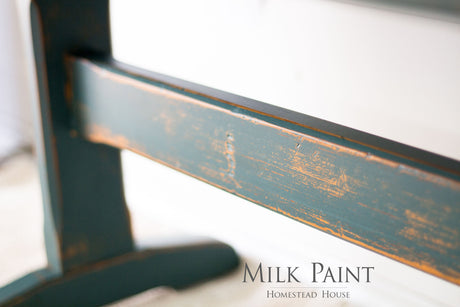 Distressed furniture leg painted in Waterloo Green Milk Paint by Homestead House; brand text in lower right corner.
