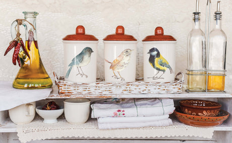 Three ceramic jars with bird motifs beside oil bottles featuring I.O.D. Whispering Willow Transfer by Iron Orchid Designs.