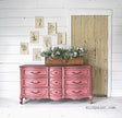 Dresser painted in Wildflower by Old Fashioned Milk Paint against a shiplap wall with plant artwork and greenery.