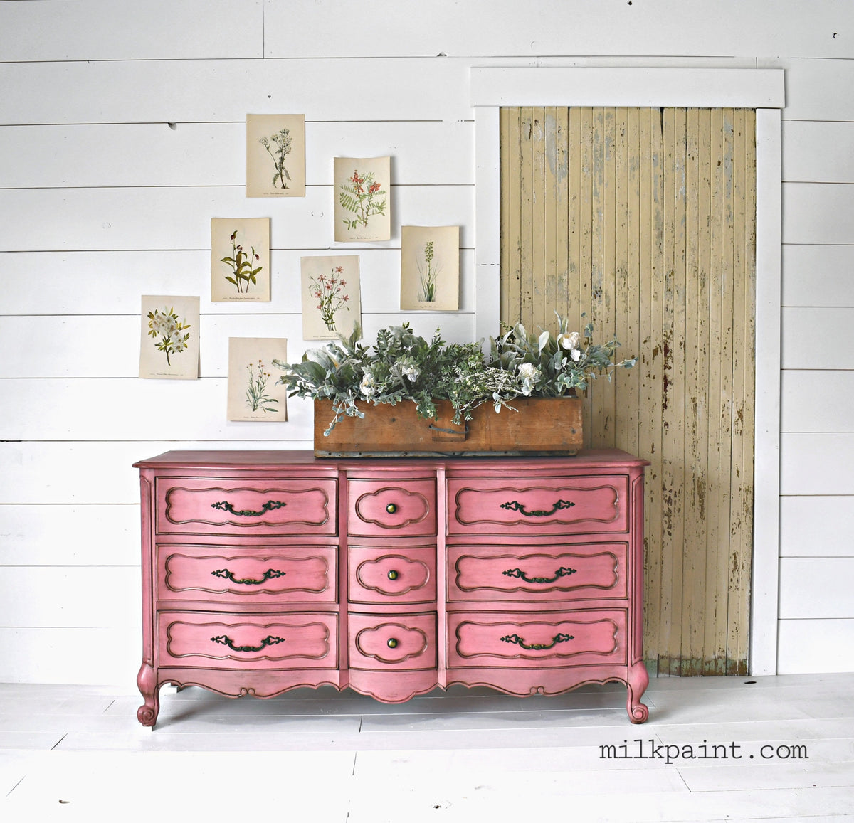 Dresser painted in Wildflower by Old Fashioned Milk Paint against a shiplap wall with plant artwork and greenery.