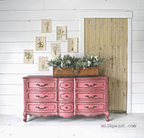 Dresser painted in Wildflower by Old Fashioned Milk Paint against a shiplap wall with plant artwork and greenery.