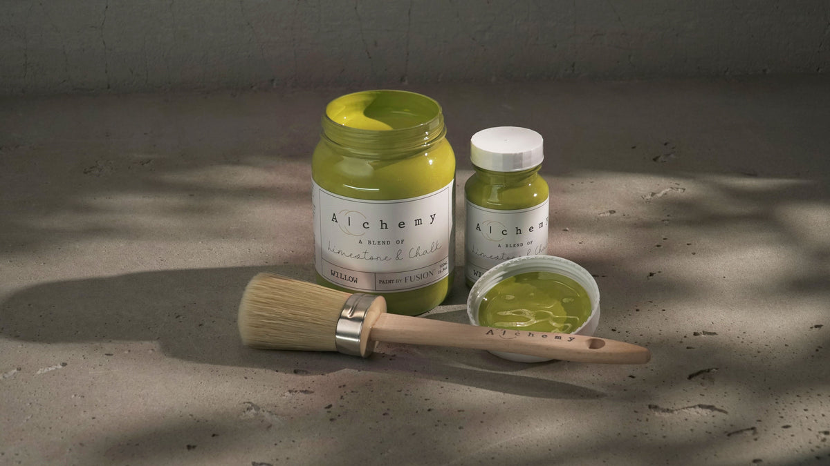 Three Willow Alchemy Paint jars by Fusion Mineral Paint with a paintbrush on a gray surface.