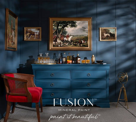 Dresser painted with Willowbank Fusion Mineral Paint in a blue room, with liquor bottles, art, red chair, and telescope.