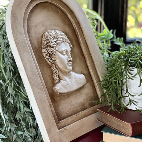 Stone arch plaque with sculpted head, displayed near books and I.O.D. Wood Gallery Blanks by Iron Orchid Designs.