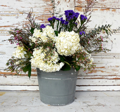 Gray bucket with flowers, shown against wall painted in Old Fashioned Milk Paint’s Zinc – Sweet Pickins shade.