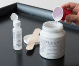 Fusion Mineral Paint Extender being poured into white Fusion paint to reduce brush strokes.