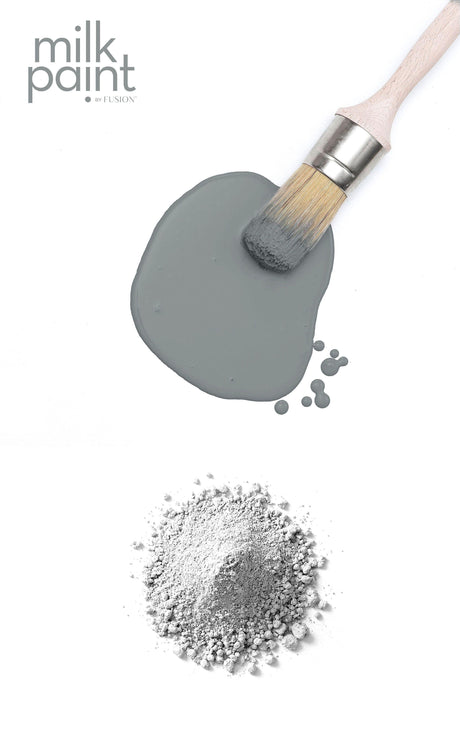 Paintbrush on Gotham Grey Milk Paint by Fusion swatch with gray powder.
