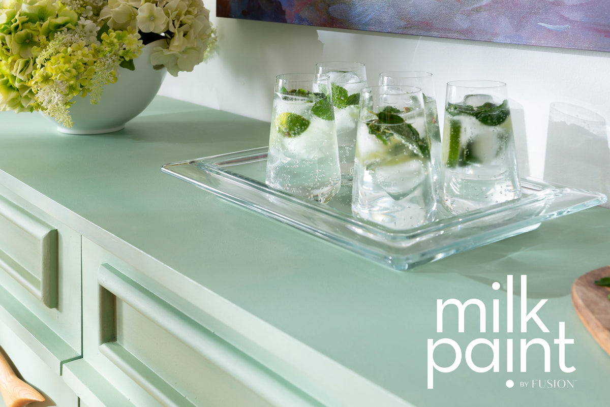 Three clear drinks with mint on Fusion Mineral Paint Mojito Milk Paint-green cabinet beside a floral bowl.