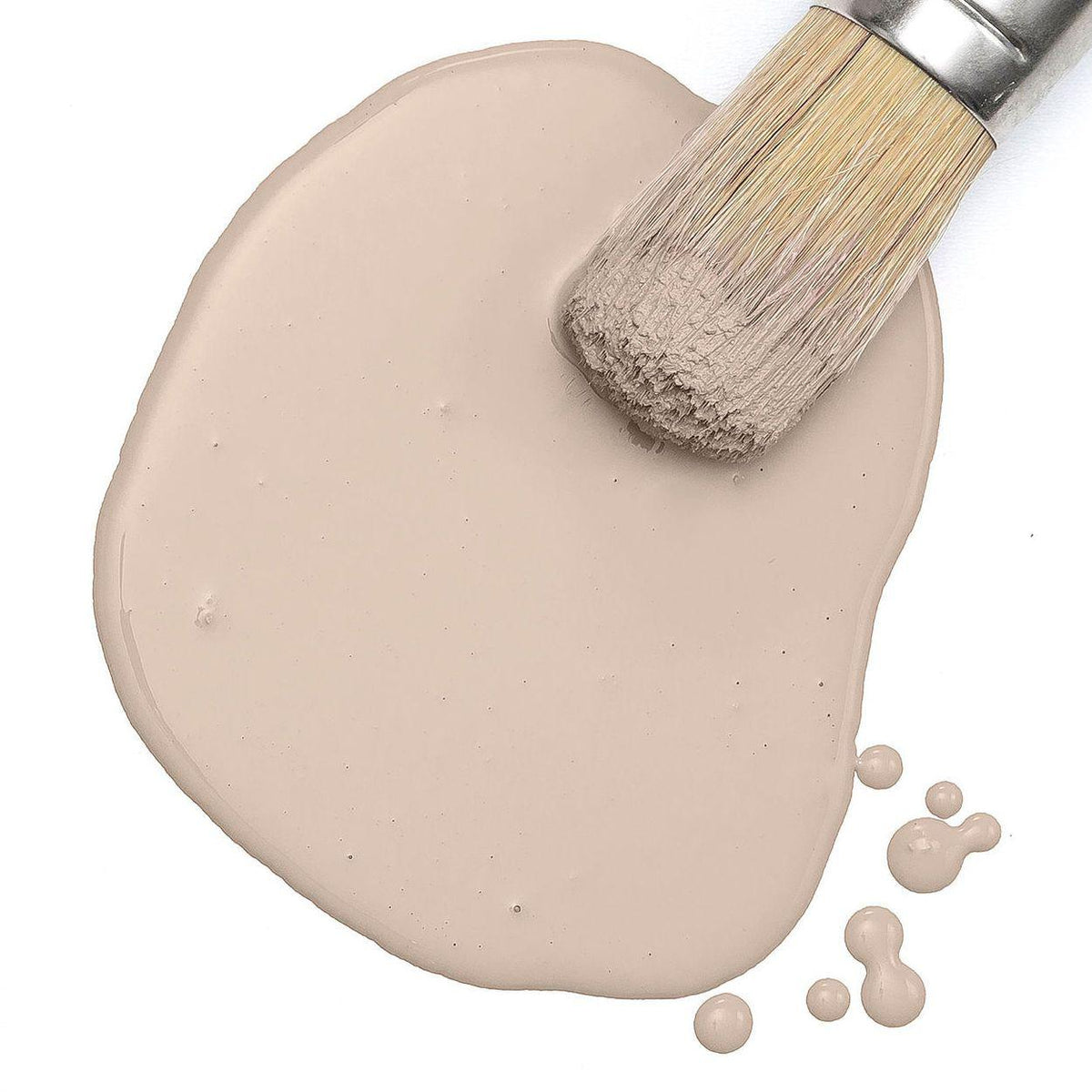 Paintbrush on Fusion Mineral Paint Oyster Bar Milk Paint puddle with drops on white background.