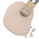Paintbrush on Fusion Mineral Paint Oyster Bar Milk Paint puddle with drops on white background.
