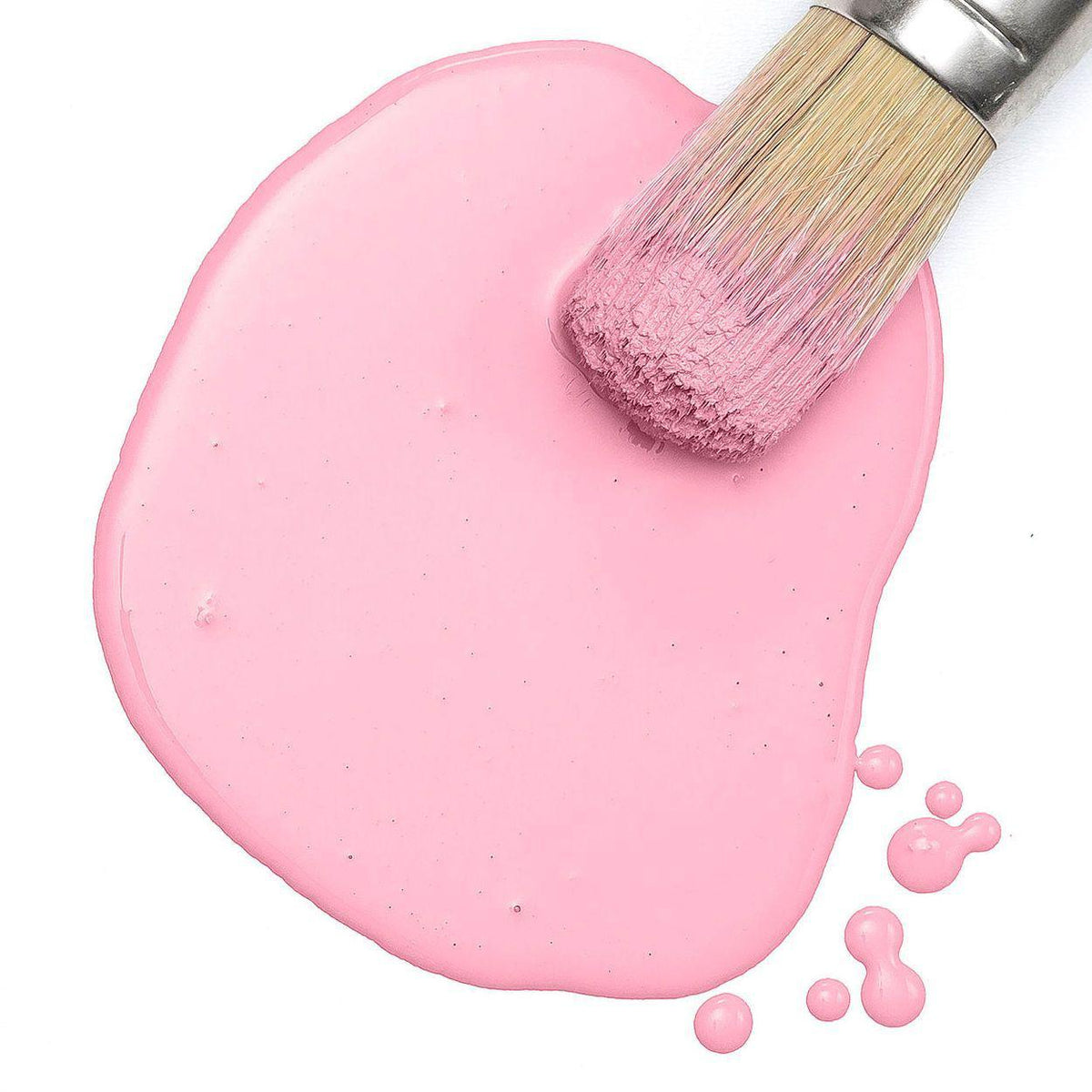 Paintbrush on Fusion Mineral Paint Palm Springs Pink Milk Paint jar with paint droplets on white background.